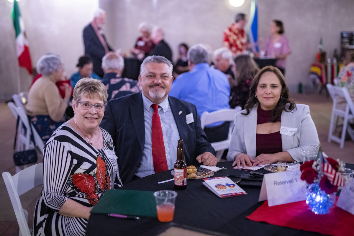 A man and two women at a social gathering seated at a table.