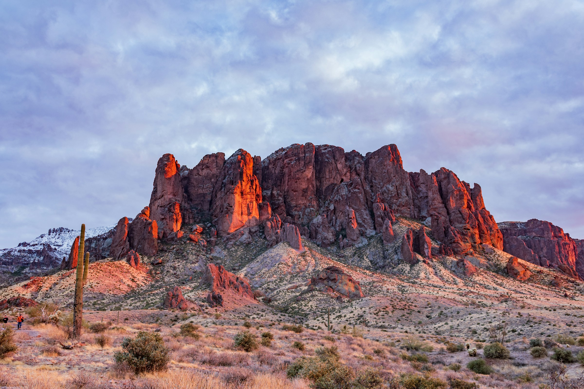 Superstition mountains east of downtown Mesa showing shadows and a dusting of snow with cloudy skies.